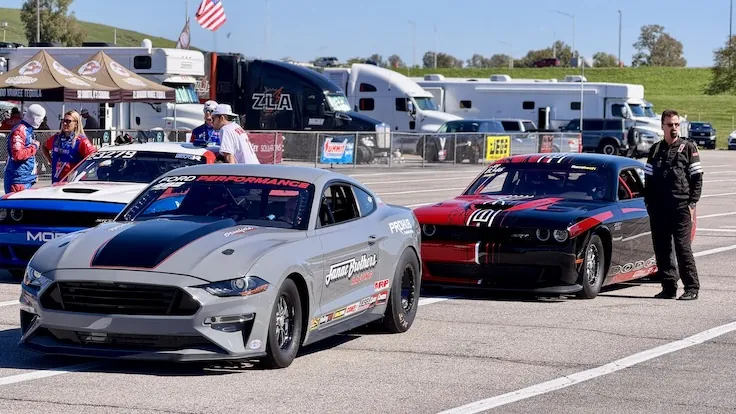 A Ford Mustang Cobra Jet and a Dodge Challenger Drag Pak side by side in the staging lanes