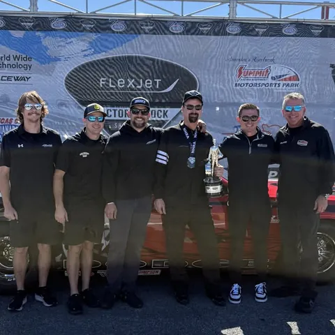 A team celebrating with the trophy at World Wide Technology Raceway